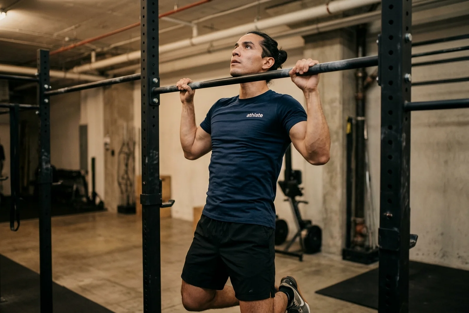 An athlate user mid pull-up on a bar.